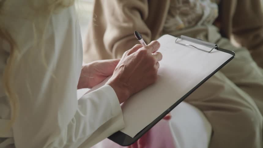 A doctor takes notes with a patient