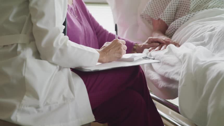 A doctor sits with a patient and takes notes