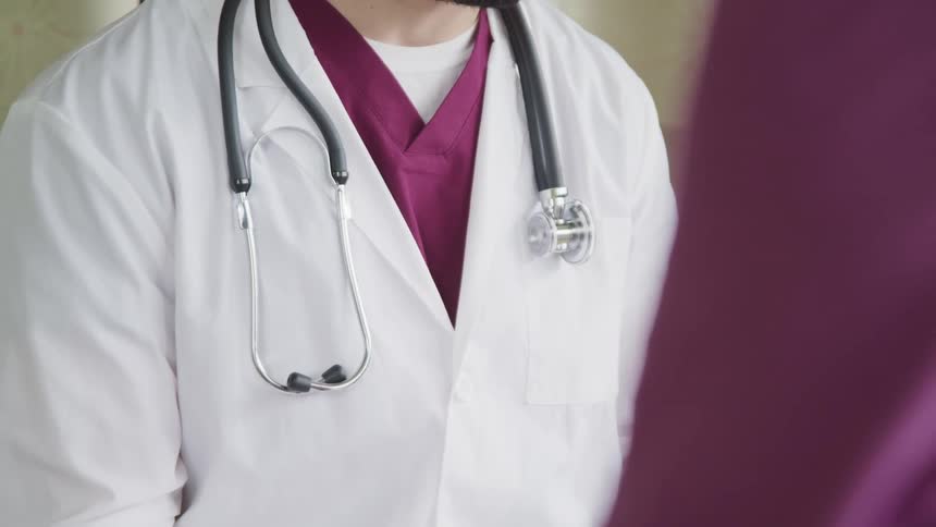 A doctor with a lab coat scrubs and stethoscope in a hospital
