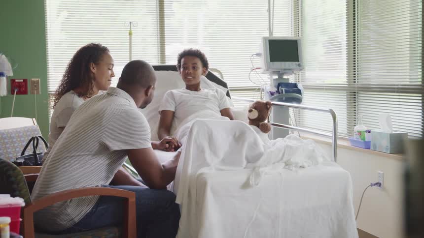 Parents sits at bedside of daughter in hospital room
