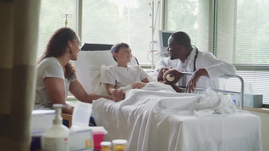 Doctor talks to a young patient and her mother in a hospital room
