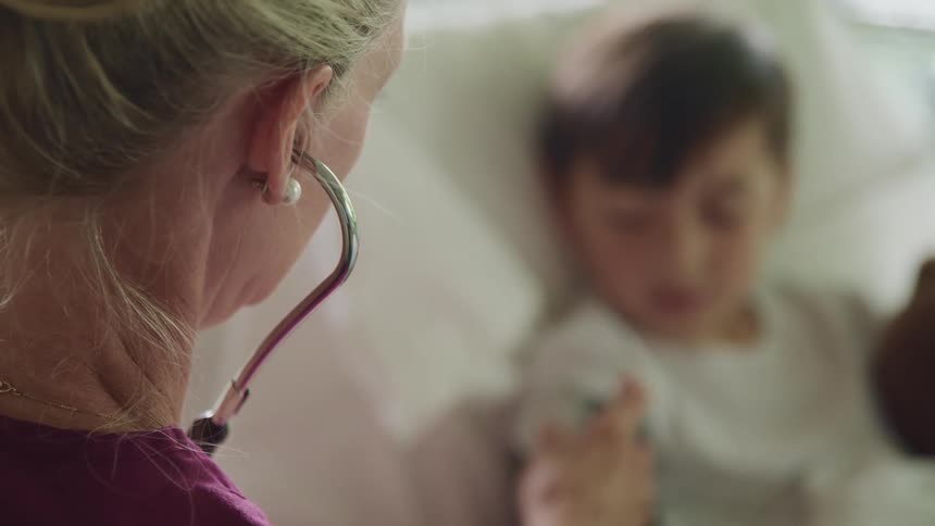 Nurse attaches a blood pressure cuff to the arm of a young boy