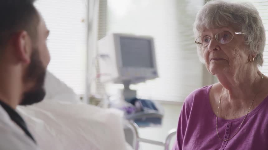 A woman talks to a doctor in a hospital room