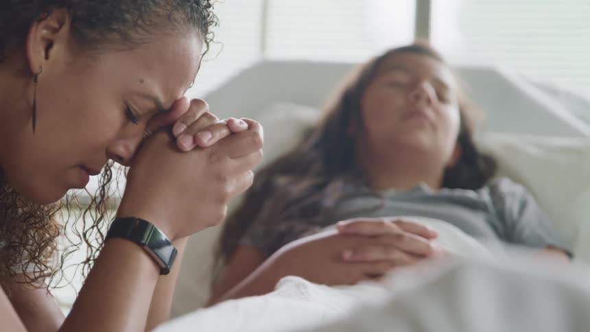A visitor is bedside to a sleeping patient