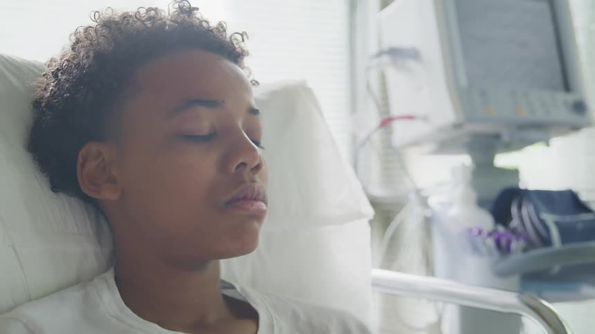 A teenage boy lays silent in a hospital bed