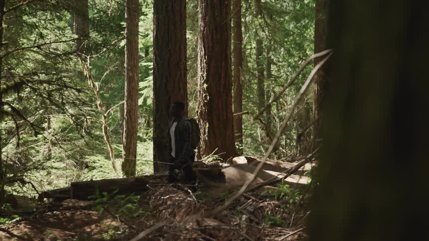 Man hikes through forest carrying backpack and fishing pole