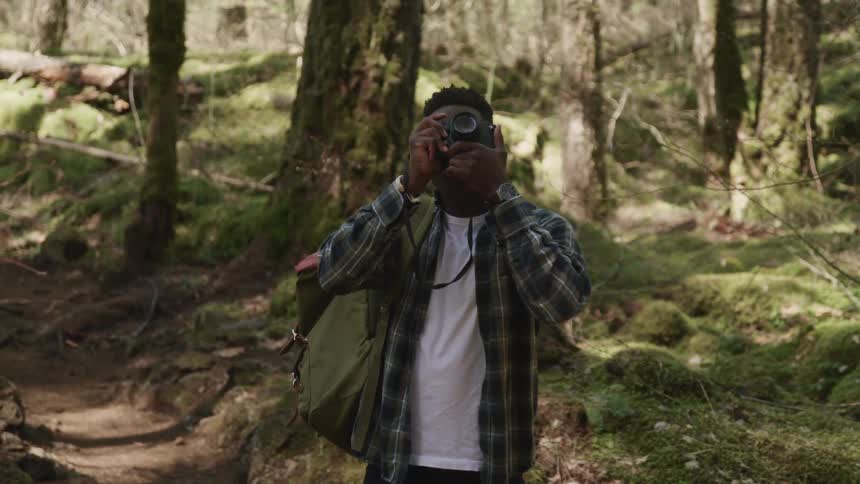 A man is taking pictures in a forest area
