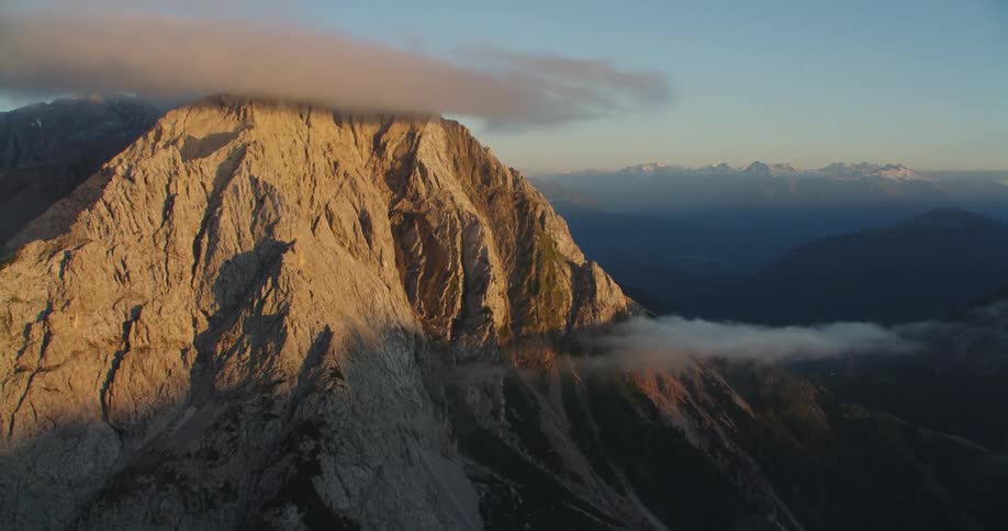 Clouds float around a mountain peak at sunrise