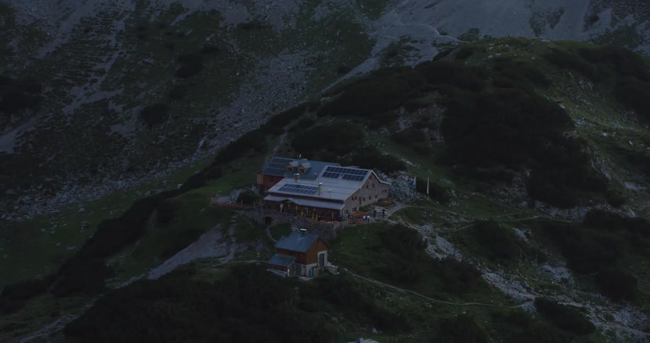 An aerial view of a remote building in mountains at night