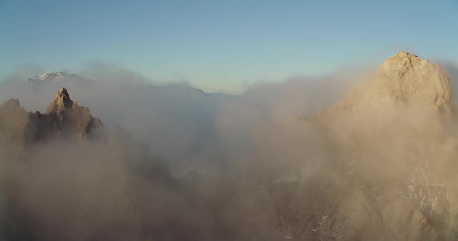 A mountain with fog and sunlight with the sky and clouds in the background