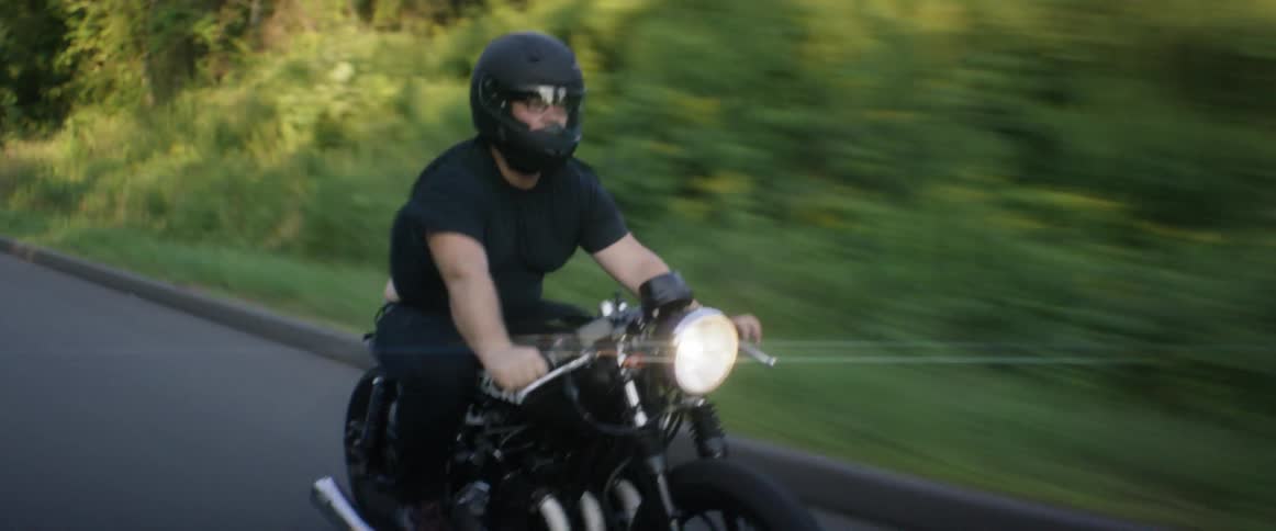 A man driving a motorcycle along a rural road
