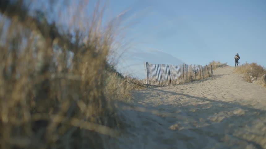A person walks up a sandy  hill