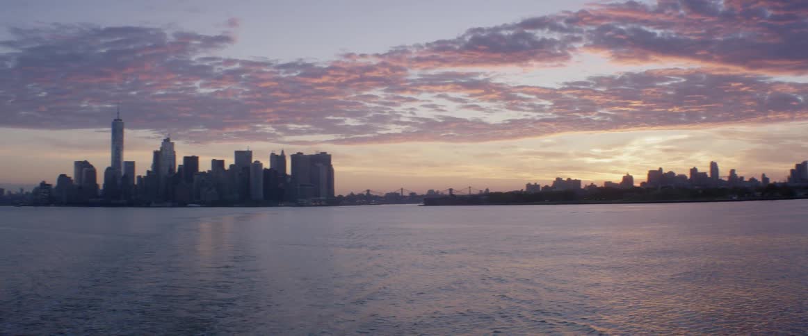 Panning of a large city across the water at sunset