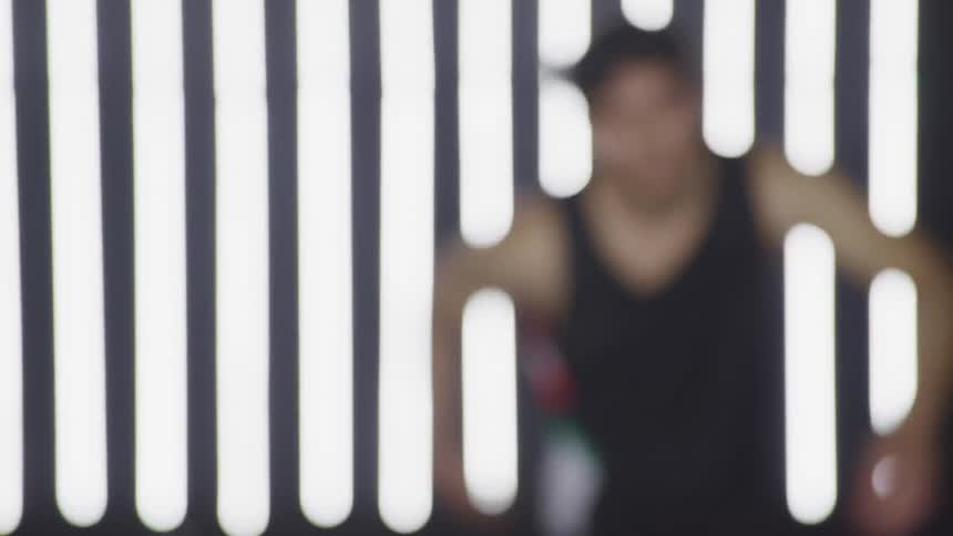 A man dances in front of an array of fluorescent lights