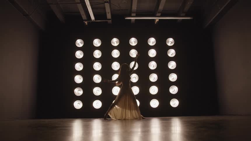 A woman dancing in front of bright lights