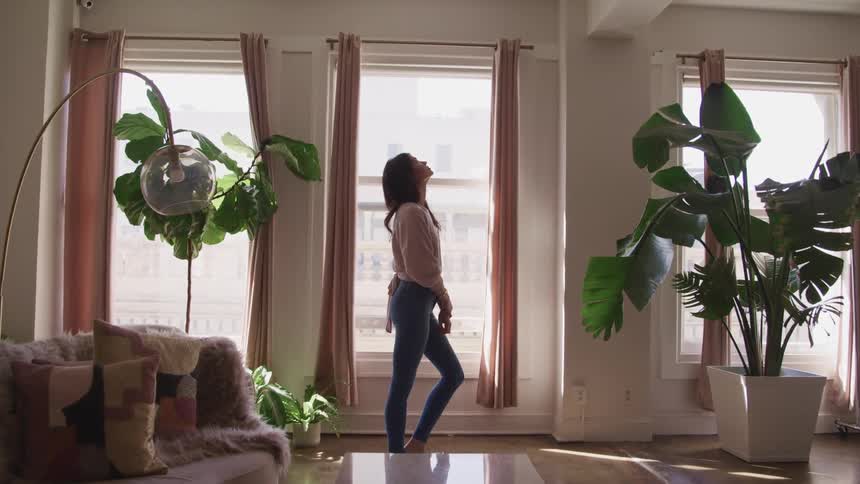 A woman standing in her home looks up at the ceiling