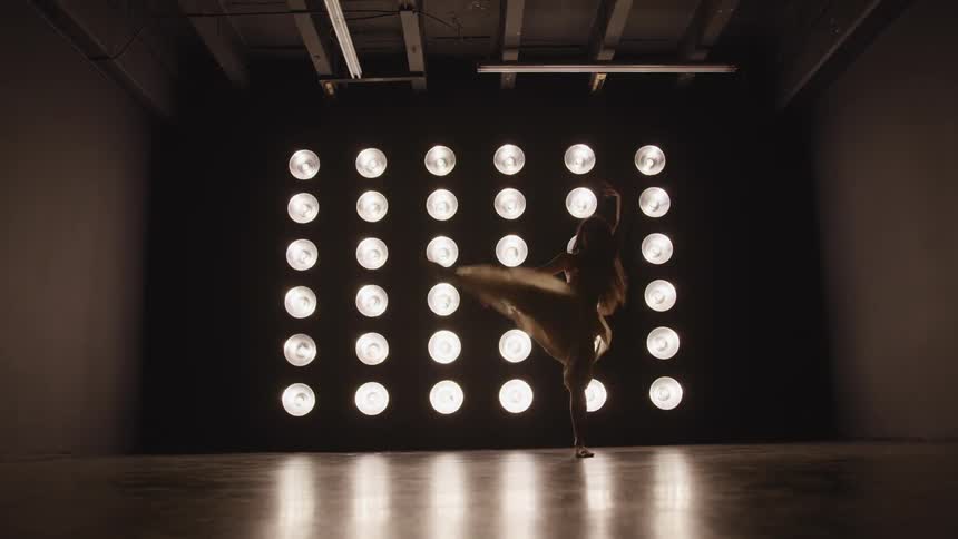 A teenage girl dancing in front of bright lights