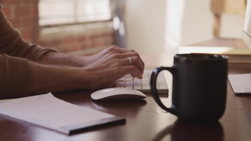 A person is typing on a computer at home