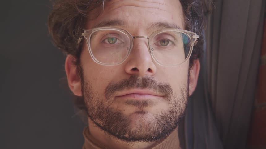 A man is standing indoors while wearing glasses