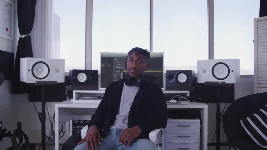 Man sitting in a chair in the audio mixing studio looks at the camera