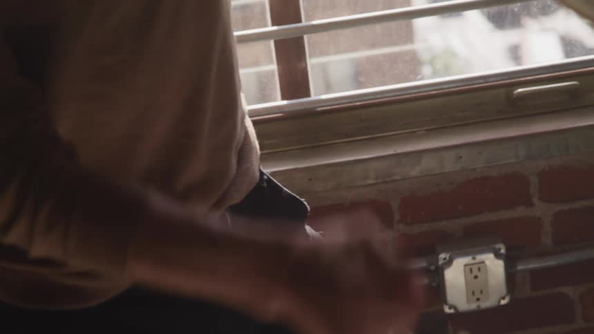 A man at home holding a book crumples up a piece of paper and throws it across the room