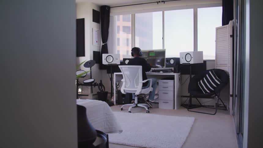 A person sits quietly at a computer desk in their room