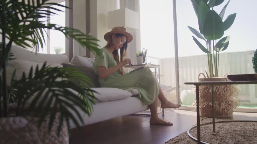 A woman is sitting on a couch and painting