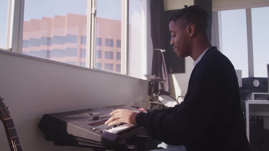 A man is playing a keyboard in a room