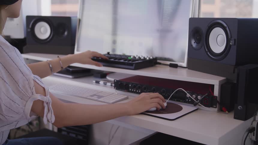 Woman uses a computer in an studio to mix and record music