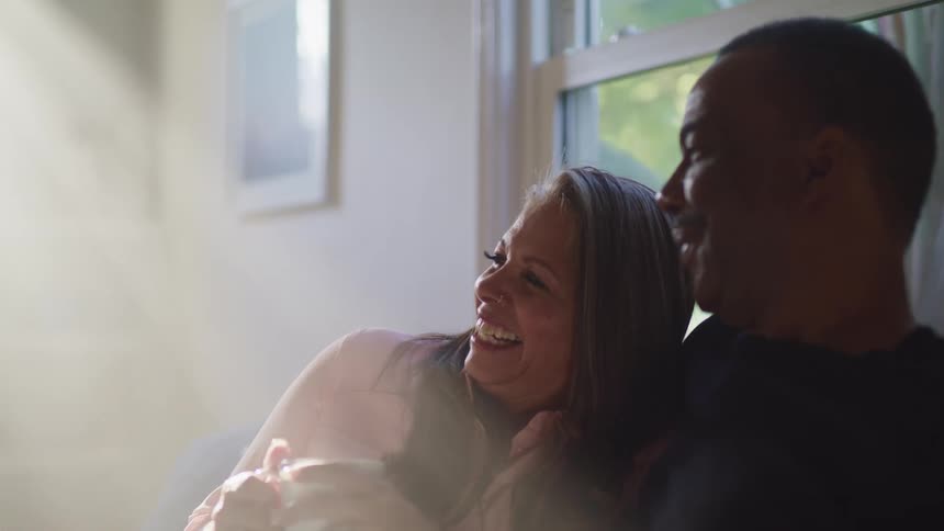 A couple sitting in a house laughing and smiling