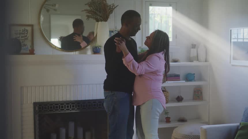 A husband and wife are dancing together in their house