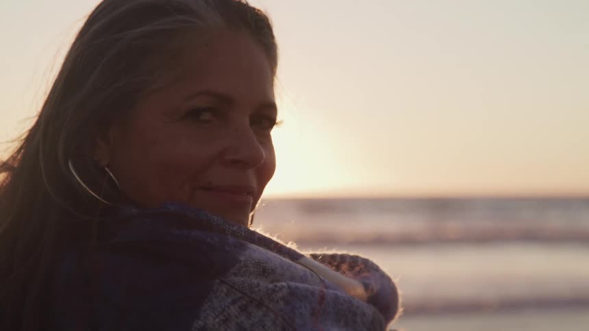 A woman smiles as she stands on the beach