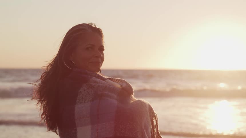 Woman wearing a shawl is near the ocean