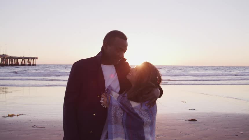 A husband and wife are hugging at the beach