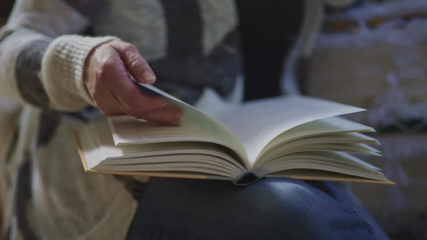 A woman is reading a book outdoors