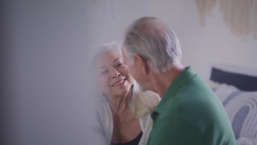 Older couple sits close together smiling and talking
