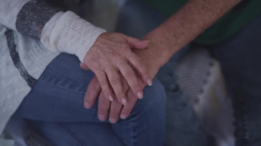 A couple hold hands while sitting