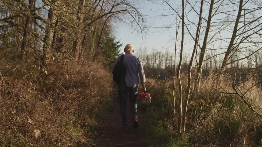 An elderly man is hiking through a forest area