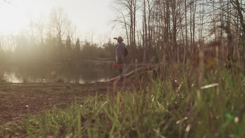 A person stands by the water looking at the sun