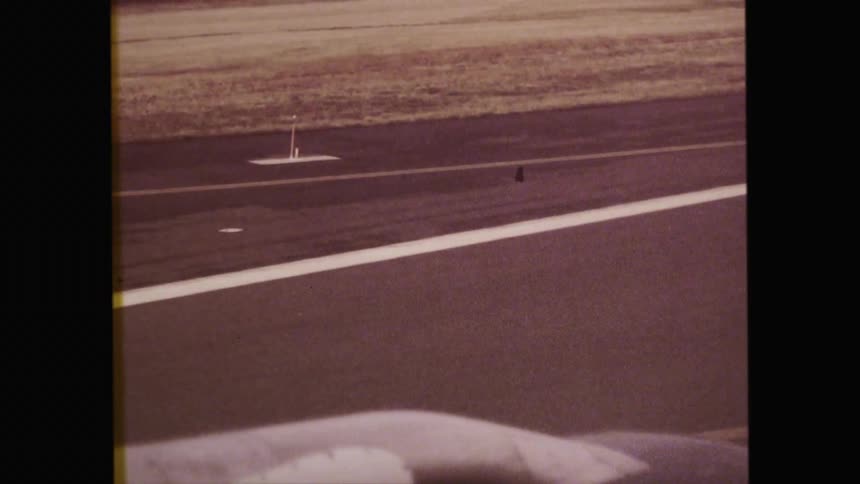 Vintage black and white filming of an airplane driving down a runway