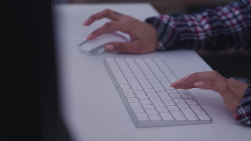 A female sitting ata table typing on a keyboard