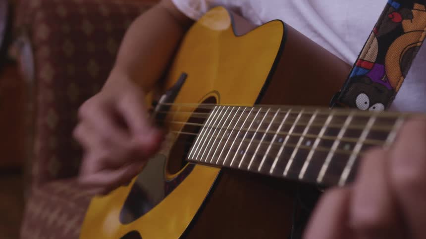 Man with a white shirt plays a guitar by pulling the strings with his fingers