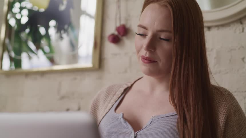 A woman sitting at home looks at her computer