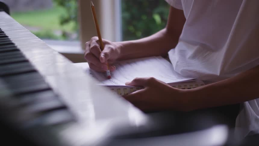 A person is erasing a music sheet by the piano