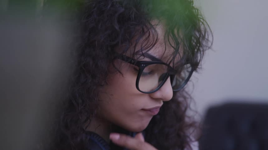A woman inside rests her chin in her hand as she thinks