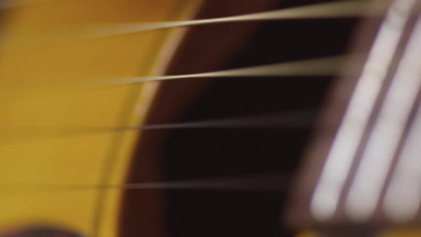 Person strums yellow colored guitar