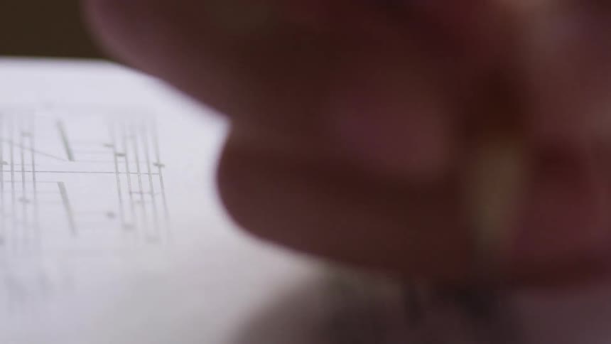 A woman makes changes to musical notes on paper