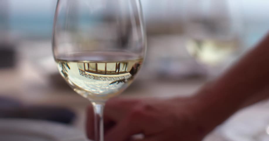 A woman puts cutlery on a table with glasses of wine on it