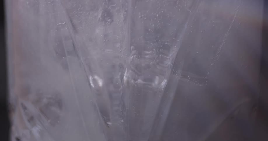 A beverage being poured in to a glass filled with ice