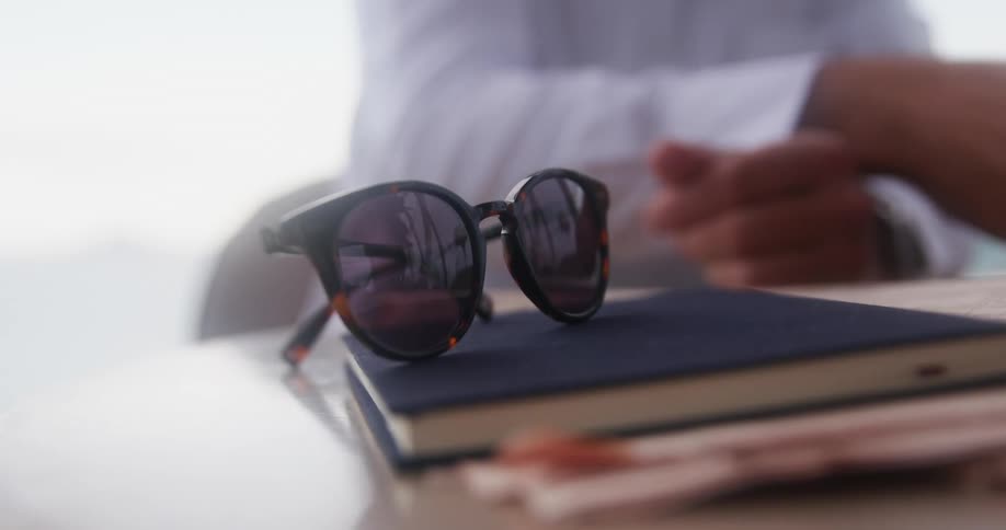 A man sitting at a table near a book and sunglasses